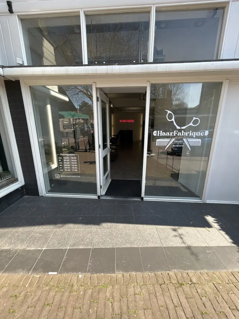 De pui van De Haar Fabrique met open deur, het logo op de ruit en de rode neonletters achterin de zaak
